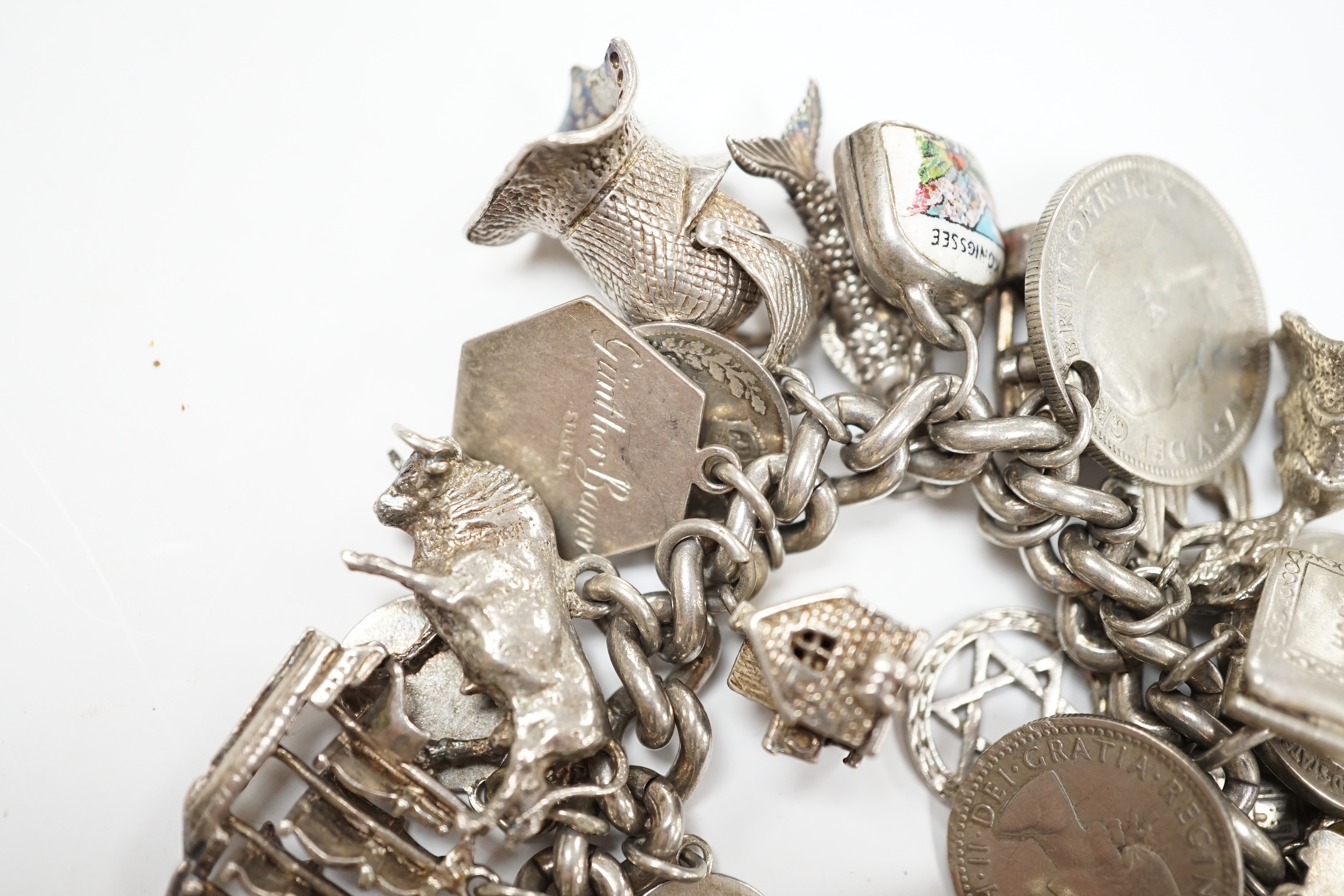 A silver charm bracelet, hung with assorted mainly white metal charms including tankard and Knight's helmet, two 'melted' ingots and a silver medallion.